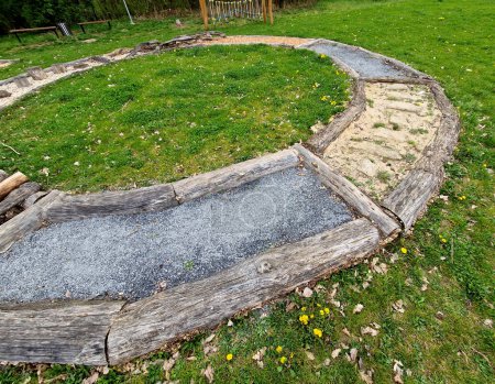 Tactile path for bare feet awakens the senses and uneven endings on the feet alternating different materials wood stone gravel sand bark in a park environment, sensoric, red, bent, curved, log