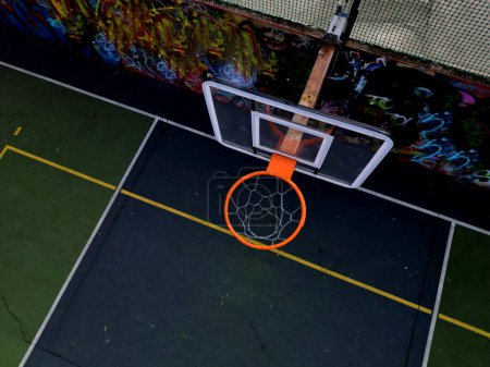 multifuncional al aire libre juegos de pelota escuela. césped artificial verde de alfombra de plástico con líneas. aros de baloncesto y goles de fútbol. alrededor de la alta red de agarre y barandillas, amarillo