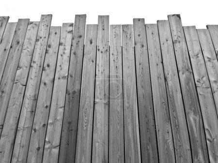 Téléchargez les photos : Un terrain à bord avec une palissade au fond. le haut de la clôture est déchiqueté des planches comme une clôture inachevée. le look bâclé est intentionnel - en image libre de droit