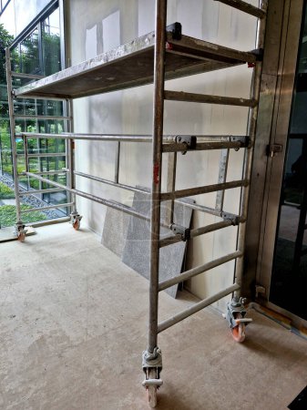Scaffolding made of galvanized pipes is installed around  building, where facades made of boards and the insulation of suspended structure are being assembled. painter, paint,ceiling, corridor, alu