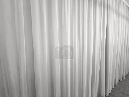 Foto de La cortina cuelga del techo al suelo. suave cortina sintética satinada que divide el espacio y forma un fondo textil suave. pesos en la parte inferior del borde de la tela - Imagen libre de derechos
