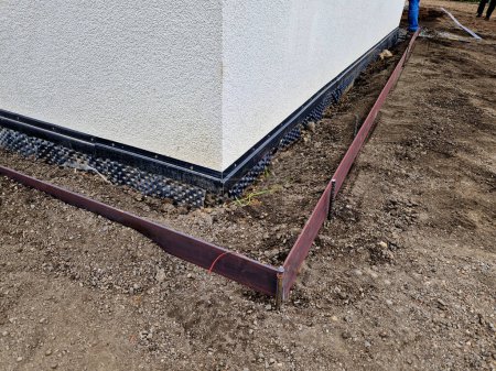 Photo for Around the house it is always necessary to create a gutter path made of gravel and pebbles. serves to absorb water and ventilate the walls of the house. installation of curb steel sheets. membrane foil - Royalty Free Image