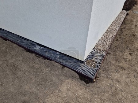 Photo for Around the house it is always necessary to create a gutter path made of gravel and pebbles. serves to absorb water and ventilate the walls of the house. installation of curb steel sheets. membrane foil - Royalty Free Image