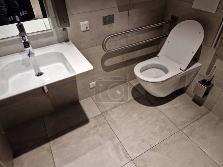 toilets for wheelchair users and disabled people have a tilting mirror that points to the ground because the height of the person sitting is lower. lever taps for easier water temperature adjustment