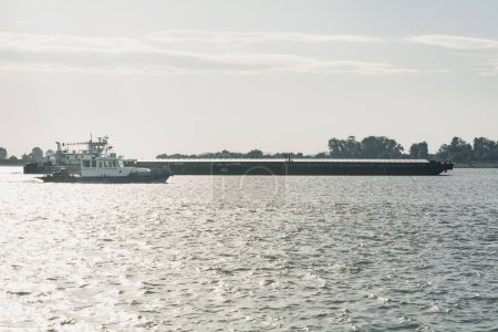 Téléchargez les photos : Galati, Roumanie : 15 septembre 2022 : Ecoexpress dans les rayons du soleil couchant - Navire pour les opérations d'assistance transbordement de produits pétroliers et collecte de déchets domestiques sur les navires. - en image libre de droit