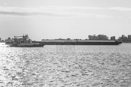 Photo for Galati, Romania: September 15, 2022: Ecoexpress in the rays of the setting sun - Vessel for assistance operations transshipment of petroleum products and collection of domestic waste on ships. B&W - Royalty Free Image