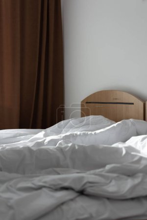 Photo for Unfolded bed in the hotel room in Romania. Bed in a hotel room with unfolded quilt in morning - Royalty Free Image