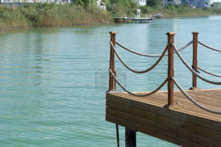 Téléchargez les photos : Masse en bois sur la rivière Lac Siutghiol, clôture en bois avec corde sur une jetée de rivière, mise au point sélective, faible profondeur de champ - en image libre de droit
