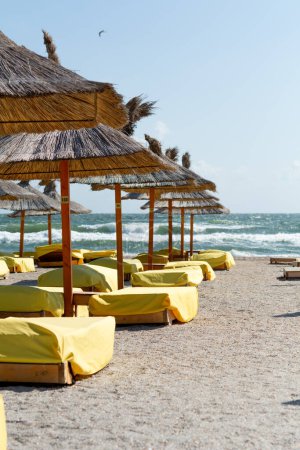 Chaises de plage recouvertes de couvertures jaunes près de la plage, sur fond de mer. Faible profondeur de champ, focalisation sélective sur les chaises longues.
