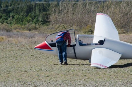 Photo for Person boarding a glider with a parachute on his back - Royalty Free Image