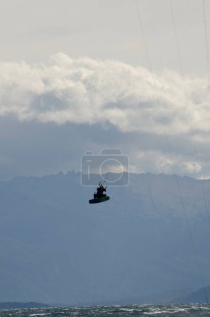 Foto de Kitesurf, deportista saltando kitesurf en un lago con montañas en el fondo - Imagen libre de derechos