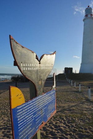 Foto de Lighthouse on the sea coast, with an informative poster about whales. - Imagen libre de derechos