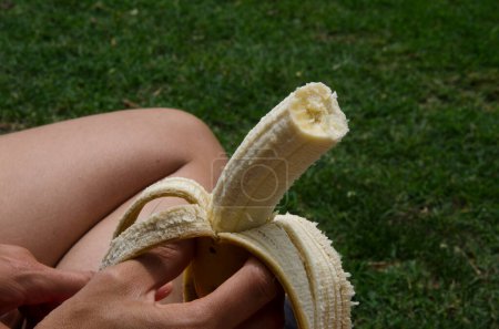 Foto de Plátano pelado en la mano de una mujer a punto de comer la fruta amarilla - Imagen libre de derechos