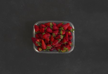 Foto de Fresas frescas sobre fondo negro en bandeja de plástico - Imagen libre de derechos