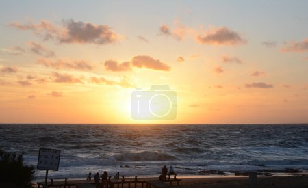 sunset at sea, with orange sky and the sun setting on the beach horizon