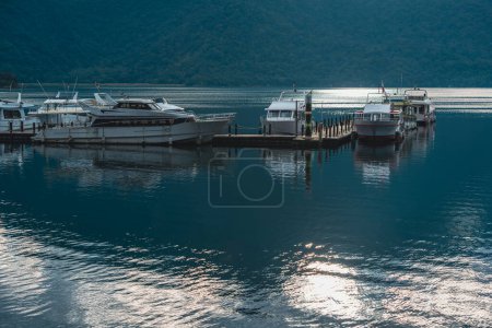 Photo for Some boats on the lake are docked at the wooden pier. The lake is very calm. Chaowu Pier, Sun Moon Lake National Scenic Area. Nantou County, Taiwan - Royalty Free Image