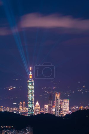 Téléchargez les photos : The light from the blue lasers on top of the tower shines in all directions. Night view of the city surrounded by mountains is hazy and dreamy.. Taipei City, Taiwan - en image libre de droit