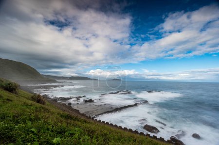 Téléchargez les photos : Rocky coast under blue sky and white clouds. White waves and light blue sea. Waimushan Seaside Scenic Area, Keelung, Taiwan - en image libre de droit