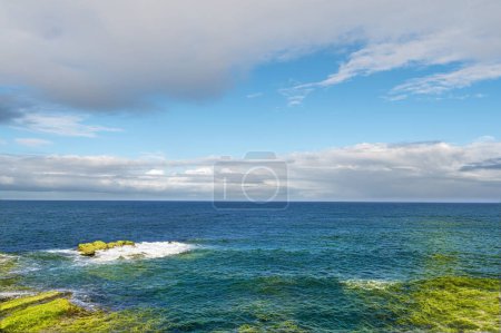 Téléchargez les photos : Rocky shore under blue sky and white clouds. White waves and moving white clouds Waimushan Seaside Scenic Area, Keelung, Taiwan - en image libre de droit