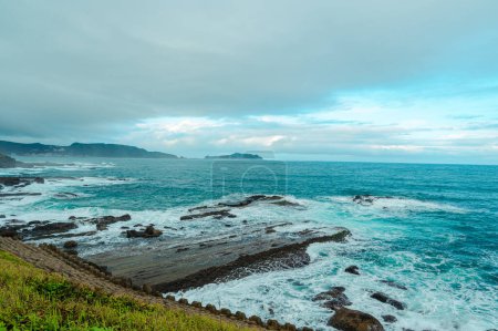 Téléchargez les photos : Rocky coast under blue sky and white clouds. White waves and light blue sea. Waimushan Seaside Scenic Area, Keelung, Taiwan - en image libre de droit