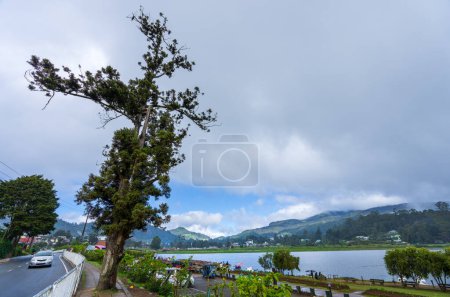 Photo for Lake Gregory, Sri Lanka - Jan. 28, 2024: A tranquil lake under a clear blue sky with visitors strolling and boating along the shore. The distant mountains add to the scenic beauty. - Royalty Free Image