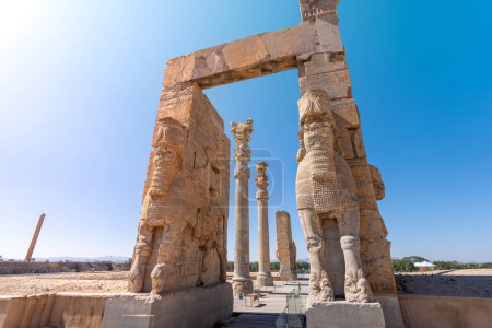 Photo for Imposing Lamassu statues stand tall, casting intricate shadows amidst the ancient ruins of Persepolis, Iran. Captured on a bright day with the blue sky and clouds. - Royalty Free Image