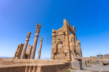 Imposing Lamassu statues stand tall, casting intricate shadows amidst the ancient ruins of Persepolis, Iran. Captured on a bright day with the blue sky and clouds.