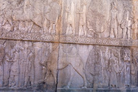 Grabados de piedra detallados que representan a personas y animales en movimiento. Un vistazo al arte antiguo, mostrando diseños intrincados y narración, Persépolis, Irán.