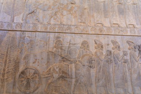 Grabados de piedra detallados que representan a personas y animales en movimiento. Un vistazo al arte antiguo, mostrando diseños intrincados y narración, Persépolis, Irán.