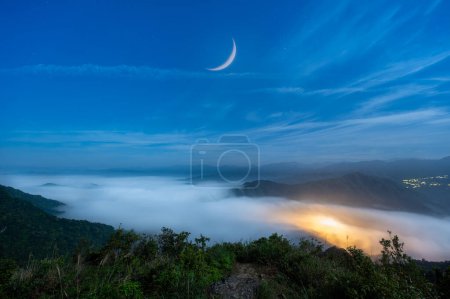 The tranquil sea of clouds and blue moon give people a mysterious feeling. View of the mountains surrounding Emerald Reservoir. Xindian District, Taiwan.