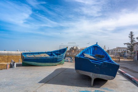 Lebendige blaue Boote sitzen an Land und Möwen fliegen über der marokkanischen Stadt Essaouira und fangen das Wesen dieser Küstenstadt ein.