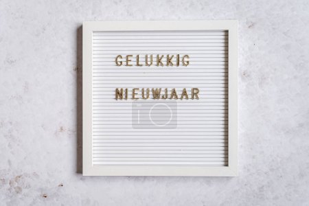 Téléchargez les photos : A white letterboard with the text in golden letters spelliing Gelukkig Nieuwjaar (Dutch for Happy New Year) - en image libre de droit