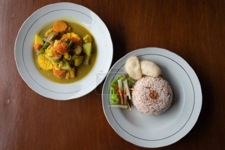 Foto de Top down view of a Sayur Kare (Balinese Vegetable Curry) on white plate with rice, horizontal - Imagen libre de derechos