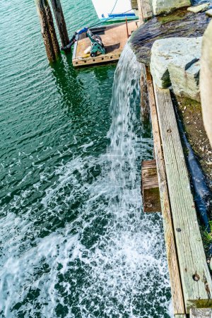 Photo for A waterfall flows down from a pier in La Conner, Washington. - Royalty Free Image