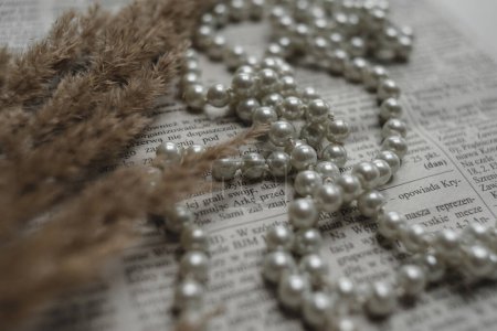 Téléchargez les photos : Une série de perles et de pierres précieuses se trouvent sur un journal, une photo dans un style rétro élégant. - en image libre de droit