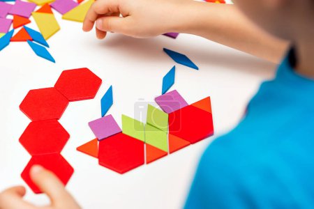 Photo for Close up of kid hands playing bright wooden tangram toy. The child collects a pattern of wooden bars. Creative baby make new forms. - Royalty Free Image