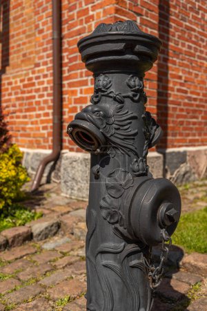 Foto de Boca de incendios de hierro fundido con la imagen de un animal sobre un fondo de una hermosa estatua de pared de ladrillo en la ciudad de Kaliningrado, Rusia - Imagen libre de derechos
