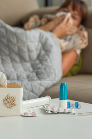 Malade femme d'âge moyen éternuement soufflant nez en cours d'exécution tenant tissu assis sur le lit, bouleversé dame mature attrapé rhume eu grippe grippe symptômes prendre des médicaments à la maison seul