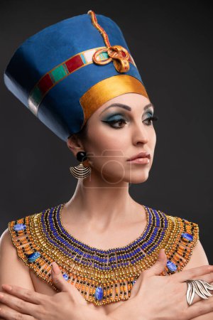 Téléchargez les photos : Belle femme aux yeux marron et maquillage du soir à l'image de la reine Cléopâtre, couronne, collier - en image libre de droit