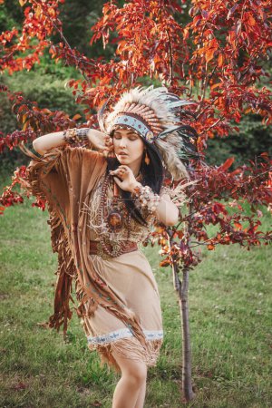 Foto de Retrato de mujer india al aire libre. Hermosa mujer étnica con cucaracha en la cabeza. Mujer vestida de boho bajo el árbol. - Imagen libre de derechos