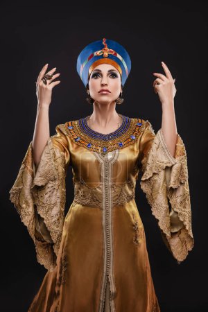 Foto de Primer plano retrato de estudio de una hermosa mujer con ojos marrones y maquillaje de noche en la imagen de la reina Cleopatra, corona, collar - Imagen libre de derechos