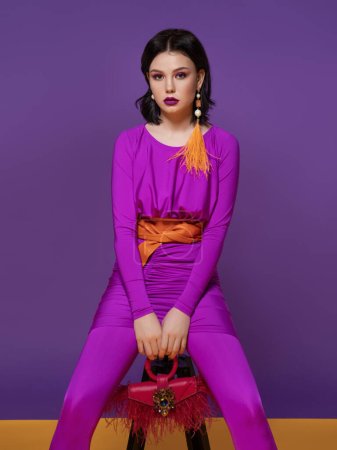 Photo for High fashion portrait of young elegant woman. Studio shot.vogue. Portrait of lovely woman wearing fashionable dress looking isolated over purple violet background - Royalty Free Image