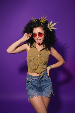 Photo for Gorgeous woman with cannabis leaves in her curly hair. Marijuana legalization. Studio shot of hipster lady. - Royalty Free Image