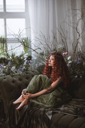 Foto de Fantasía mujer de pelo rojo con velas, flores y plantas, princesa druida fantasía oscura - Imagen libre de derechos