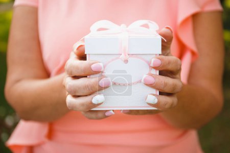 Foto de Mujer sostiene en sus manos una caja de regalo atada con una cinta el día de la boda - Imagen libre de derechos