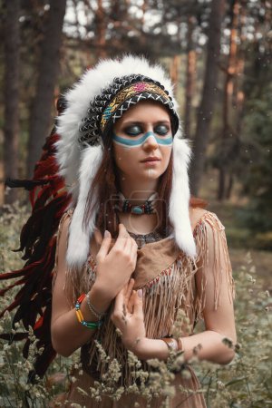 Foto de Hermosa mujer india en cucaracha, vestido con flecos y maquillaje en su cara, se encuentra en el bosque - Imagen libre de derechos