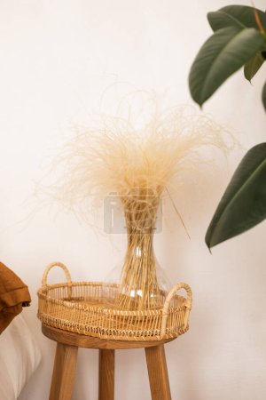 Photo for Beautiful interior with a wicker wicker basket, a wicker chair with a wicker basket, a vase with a white vase, on a white table. - Royalty Free Image