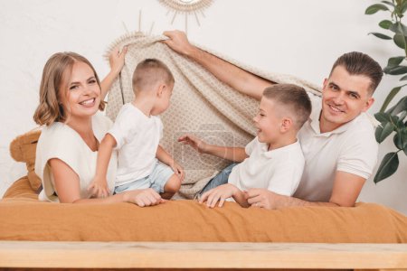 Foto de Padres jugando, divirtiéndose con sus hijos. Familia feliz en el dormitorio en la cama juntos. - Imagen libre de derechos