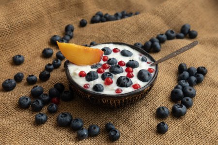 Photo for Plates with yogurt and berries on the table, on a coarse cloth, healthy breakfast - Royalty Free Image