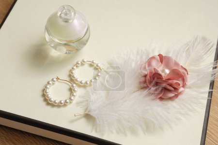 Foto de Pendientes de perlas blancas, perfume y una pluma blanca con una flor rosa en la caja, regalo de boda - Imagen libre de derechos
